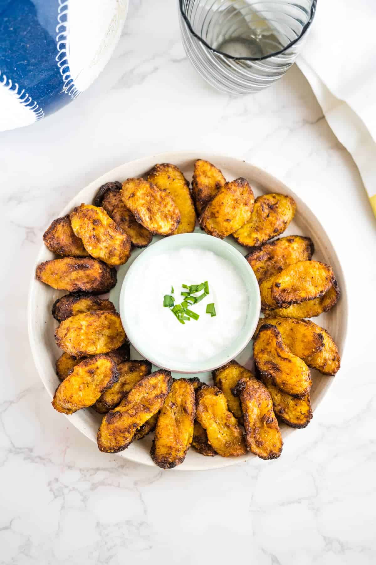 Air fried plantains on a plate with dipping sauce.