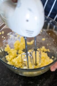 The electric mixer whirs smoothly, blending yellow dough in a glass bowl perched on the black countertop, ready to transform into a delightful sorrel fruit cake.