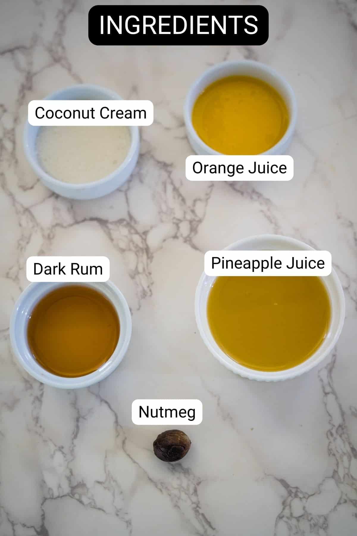 Labeled ingredients on a marble surface include coconut cream, orange juice, dark rum, pineapple juice, and a nutmeg.