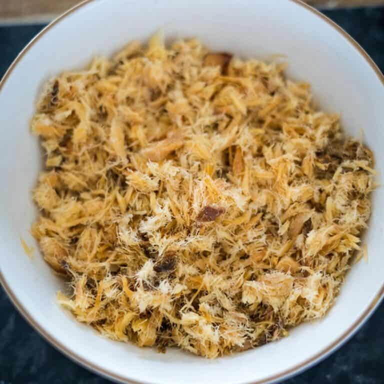 A bowl of shredded dried fish is placed on a dark surface.