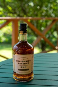A bottle of Chairman's Reserve Original Saint Lucia Rum sits on a green outdoor table with a blurred garden background.