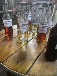 Several labeled bottles, showcasing different stages and components of Saint Lucia rum, are arranged on a round wooden table. A person stands in the background.