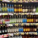 Shelves in a store display various brands and types of rum, including light, dark, and flavored options such as Saint Lucia rum, with price tags visible below each bottle.
