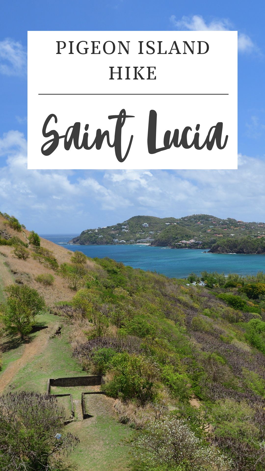 View of Pigeon Island, Saint Lucia, featuring the scenic Pigeon Island hike—a trail winding through green hills, scattered trees, and blue sea under a partly cloudy sky. A sign reads "Pigeon Island Hike, Saint Lucia.